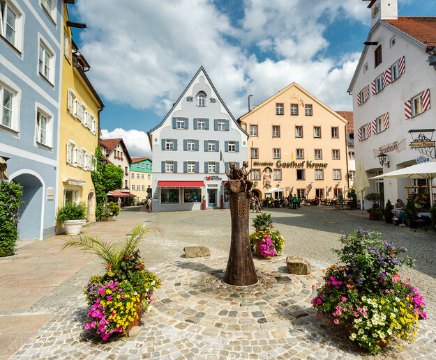 Der Schrannenplatz in Füssen mit historischen Gebäuden und Blumenkästen. Ein idyllischer Ort im Herzen der Stadt.