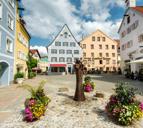 Der Schrannenplatz in Füssen mit historischen Gebäuden und Blumenkästen. Ein idyllischer Ort im Herzen der Stadt.