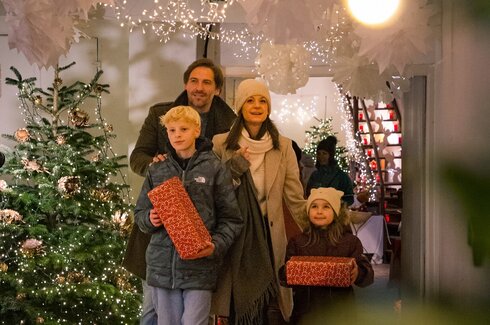 Das Bild zeigt eine vierköpfige Familie die durch eine weihnachtlich geschmückte Passage läuft.
