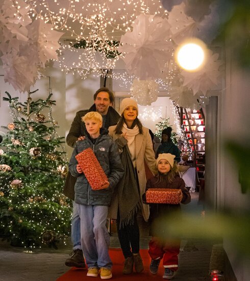 Das Bild zeigt eine vierköpfige Familie die durch eine weihnachtlich geschmückte Passage läuft.