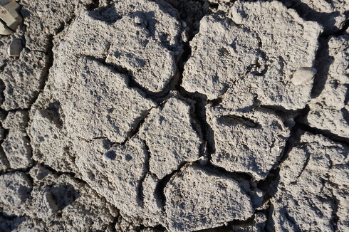 Das Bild zeigt einen ausgetrockneten Boden, dessen Erde aufgrund von Wassermangel aufgeplatzt ist.