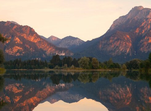 Das Bild zeigt den Blick über den Forggensee auf Sch.loss Neuschwanstein und die benachbarten Alpengipfel bei einer Abendfahrt mit der Forggensee-Schifffahrt.