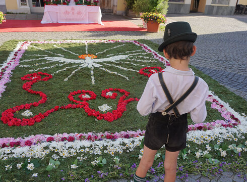 Ein Bub in Tracht steht vor dem Fronleichnams-Blumenteppich auf dem Schrannenplatz in Füssen.