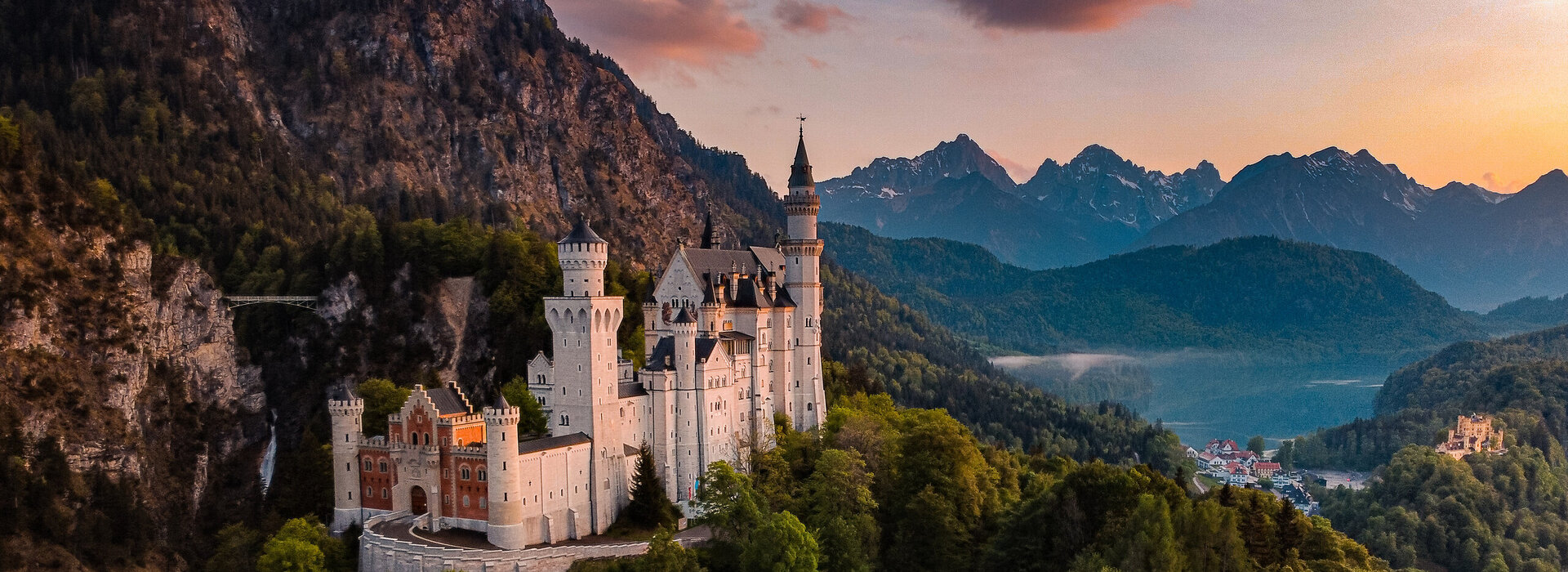 Panoramablick auf das Märchenschloss Neuschwanstein inmitten grüner Berge. Ein magischer Ort in Bayern.