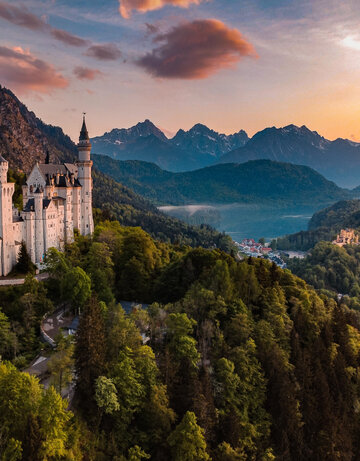 Panoramablick auf das Märchenschloss Neuschwanstein inmitten grüner Berge. Ein magischer Ort in Bayern.