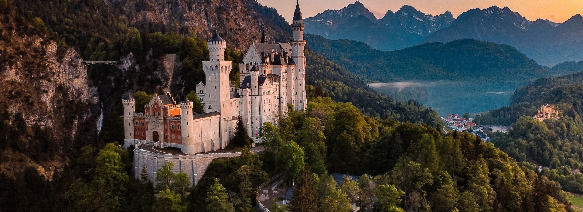 Panoramablick auf das Märchenschloss Neuschwanstein inmitten grüner Berge. Ein magischer Ort in Bayern.