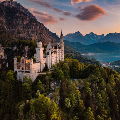 Panoramablick auf das Märchenschloss Neuschwanstein inmitten grüner Berge. Ein magischer Ort in Bayern.