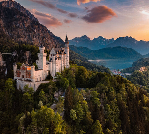 Panoramablick auf das Märchenschloss Neuschwanstein inmitten grüner Berge. Ein magischer Ort in Bayern.