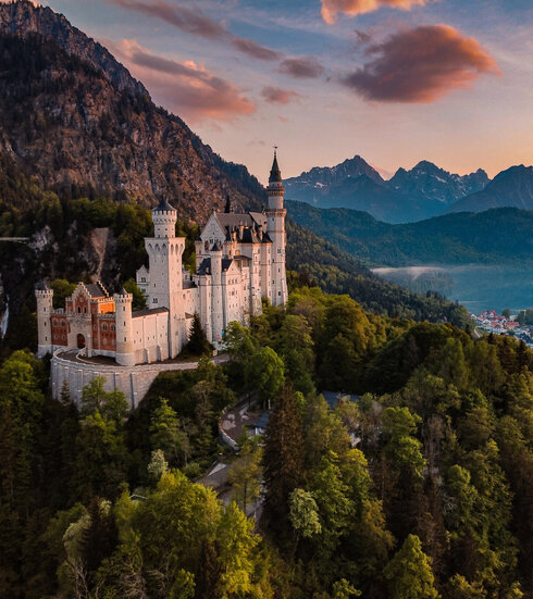 Panoramablick auf das Märchenschloss Neuschwanstein inmitten grüner Berge. Ein magischer Ort in Bayern.