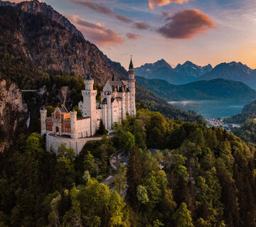 Panoramablick auf das Märchenschloss Neuschwanstein inmitten grüner Berge. Ein magischer Ort in Bayern.