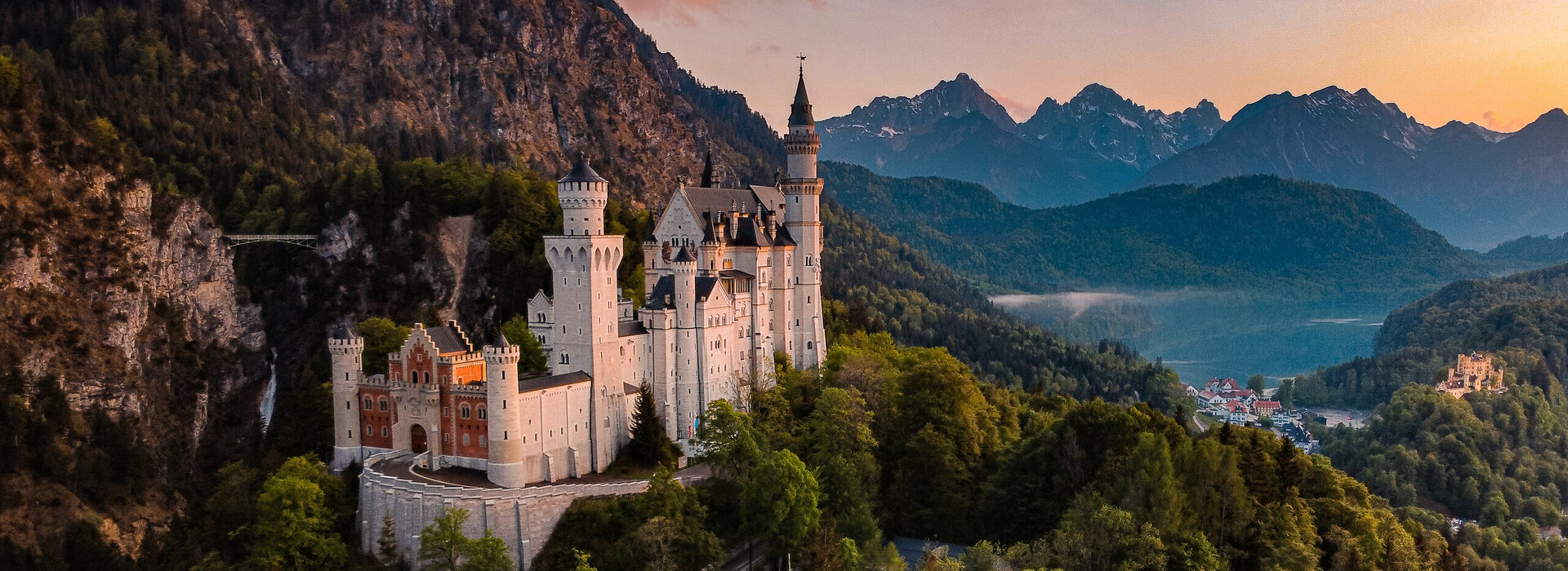 Panoramablick auf das Märchenschloss Neuschwanstein inmitten grüner Berge. Ein magischer Ort in Bayern.