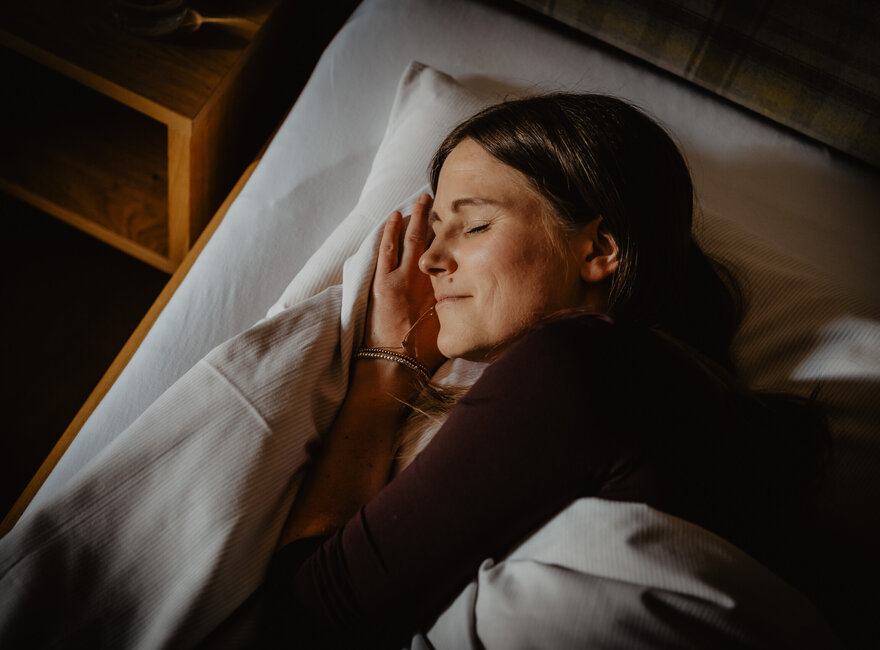 Eine Frau schläft tief in einem gemütlichen Bett. 