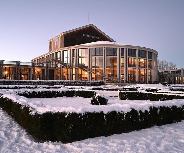 Auf dem Bild ist der verschneite Barockgarten sowie der runde Kubus des Festspielhaus Neuschwanstein zu sehen