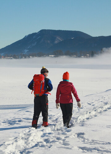 Zwei Personen wandern über den mit Schnee bedeckten Forggensee