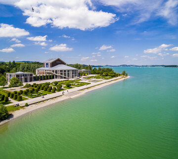 Auf dem Bild ist das Festspielhaus Füssen vor dem Ufer des Forggensees zu sehen