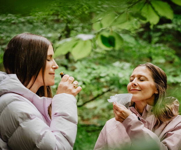 Zwei Frauen riechen an duftenden Säckchen im Wald