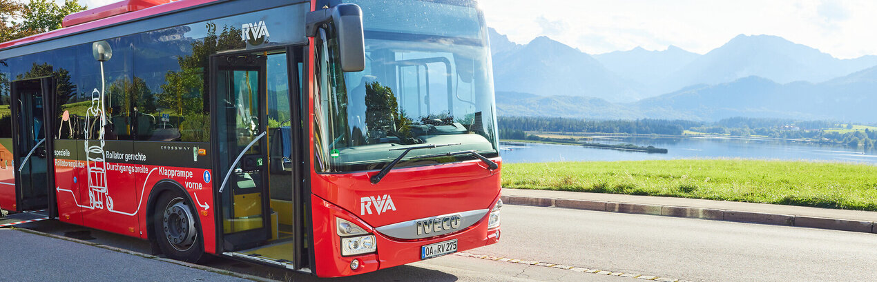 Foto eines Nahverkehrs-Busses mit dem Forggensee und den Ammergauer Alpen im Hintergrund