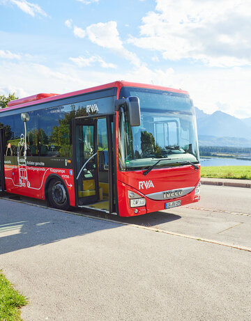 Foto eines Nahverkehrs-Busses mit dem Forggensee und den Ammergauer Alpen im Hintergrund