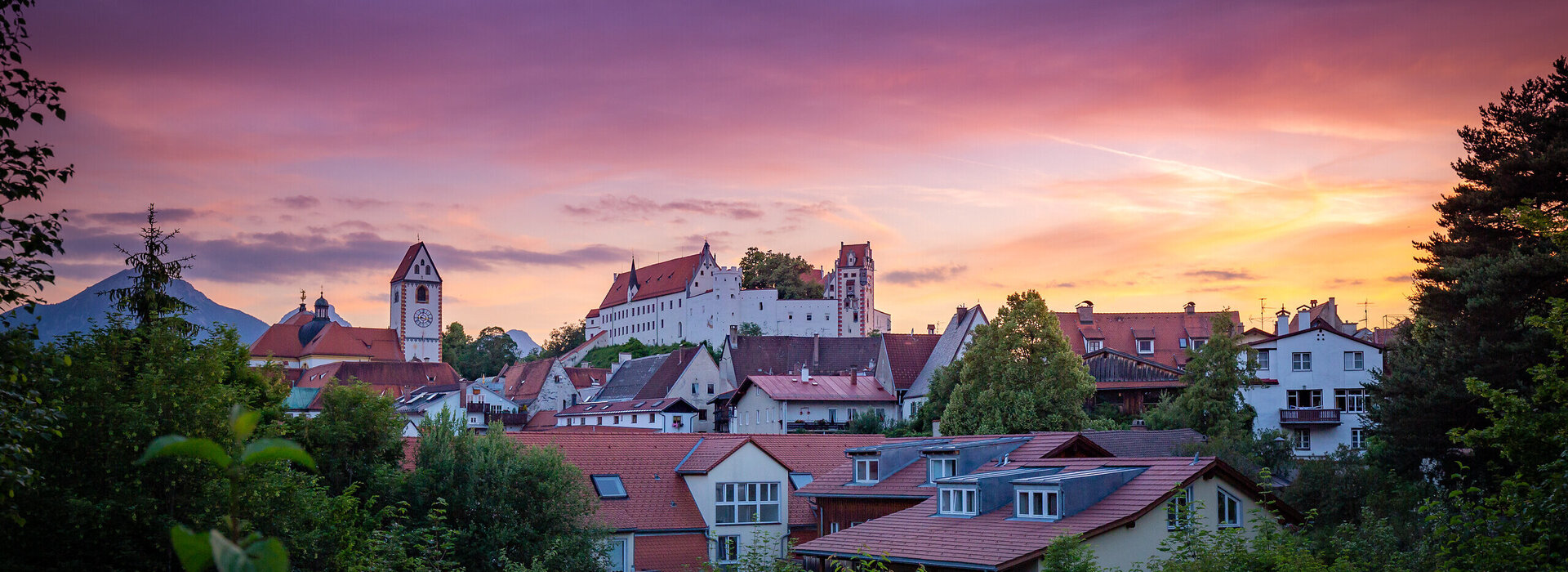 Das Hohe Schloss thront über die farbenprächtige Altstadt Füssens. Ein atemberaubender Sonnenuntergang verstärkt die Schönheit der Stadt.