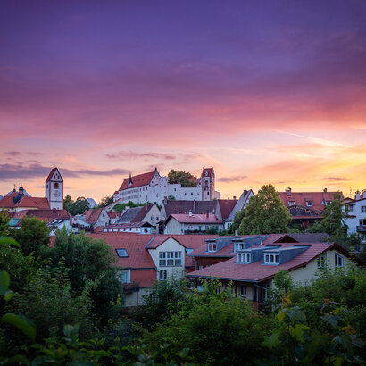 Das Hohe Schloss thront über die farbenprächtige Altstadt Füssens. Ein atemberaubender Sonnenuntergang verstärkt die Schönheit der Stadt.