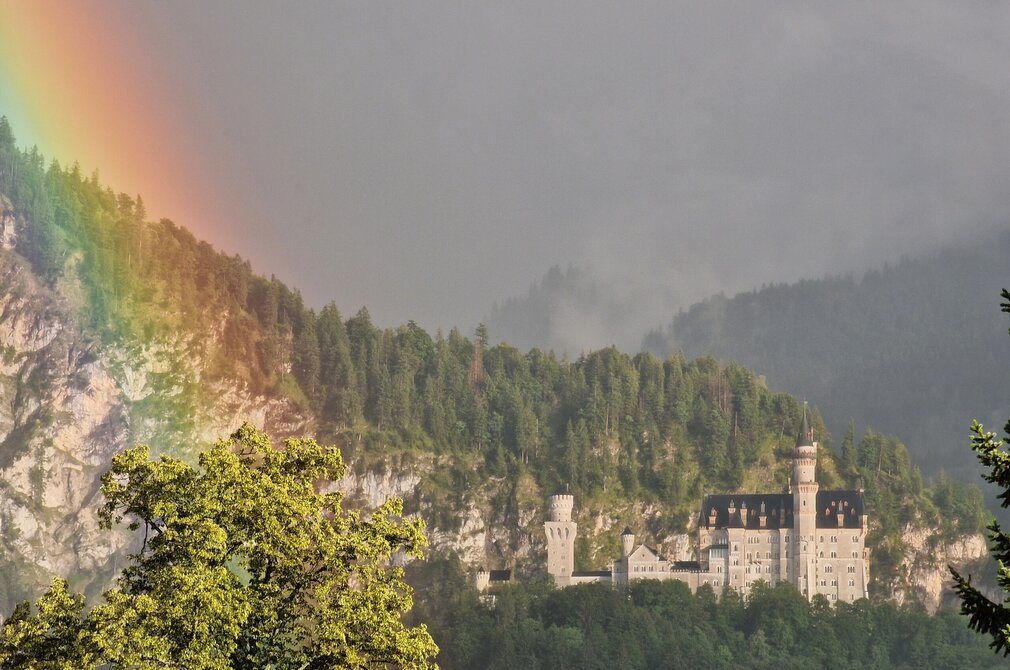 Das Foto zeigt Schloss Neuschwanstein bei Füssen im Allgäu mit einem Regenbogen.
