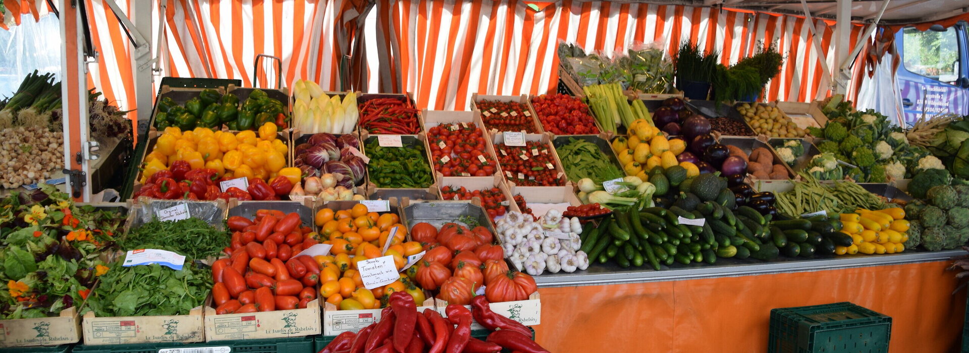 Ein lebendiger Marktstand bietet eine Fülle von Farben und Aromen mit einer beeindruckenden Auswahl an frischen Produkten. Die Fülle der Waren deutet auf eine reiche Ernte und eine lebendige Marktatmosphäre hin.