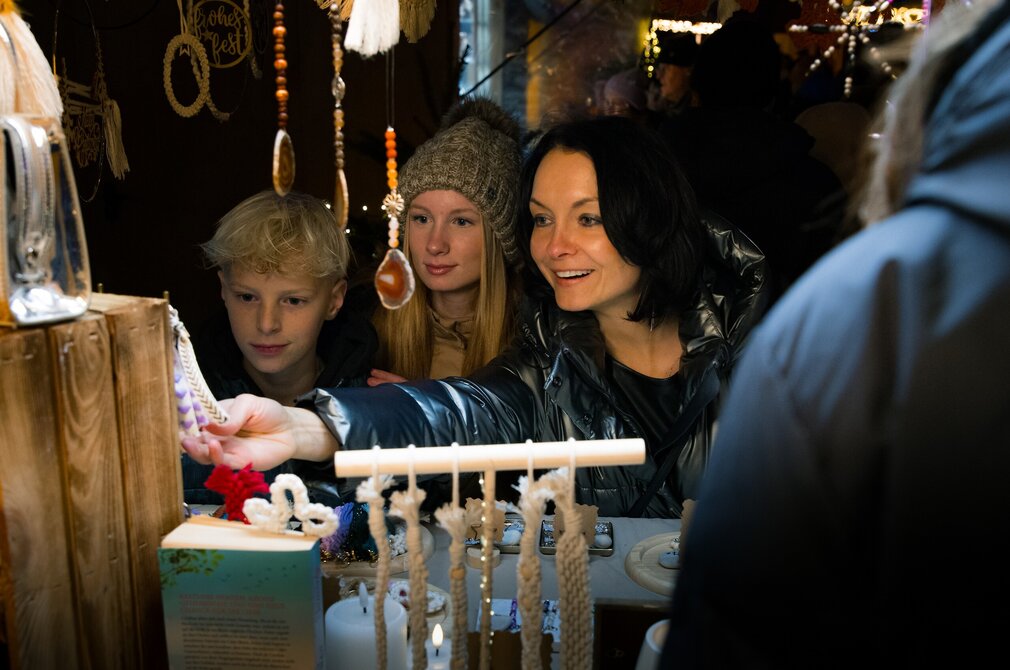 Das Foto zeigt eine Frau un dzwei Kinder an einem Marktstadt auf dem Füssener Adventsmarkt.