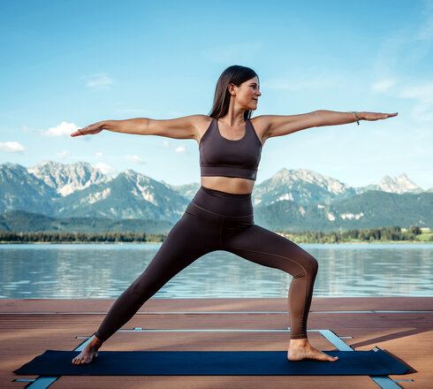 Das Bild zeigt eine Frau, die auf einer Plattform im Hopfensee Yoga praktiziert