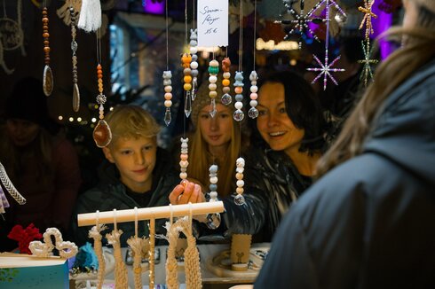 Das Bild zeigt eine Frau und zwei Kinder an einer Bude auf einem Weihnachtsmarkt.