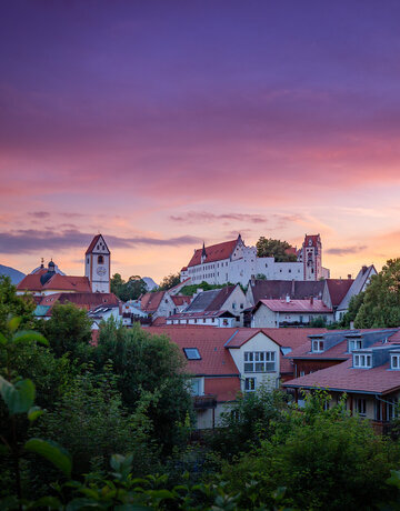 Das Hohe Schloss thront über die farbenprächtige Altstadt Füssens. Ein atemberaubender Sonnenuntergang verstärkt die Schönheit der Stadt.