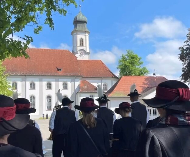 Hier marschieren die Musiker geordnet in die Kirche ein. Die Musiker sind von hinten mit dem Rücken zu sehen.