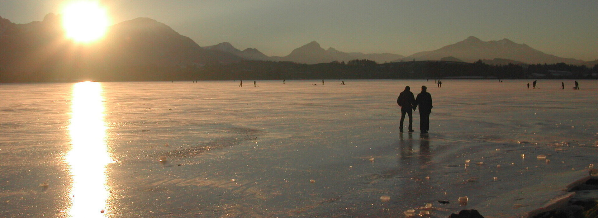 Das Bild zeigt den zugefrorenen Hopfensee bei Füssen vor den Alpengipfeln
