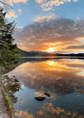 Das Bild zeigt den Weißensee Und den Füssener Ortsteil Weißensee im Abendlicht. 