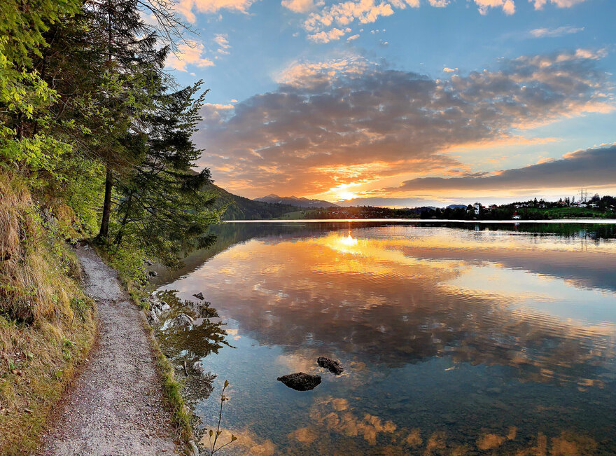 Das Bild zeigt den Weißensee Und den Füssener Ortsteil Weißensee im Abendlicht. 
