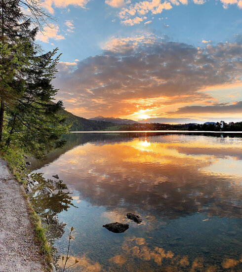 Das Bild zeigt den Weißensee Und den Füssener Ortsteil Weißensee im Abendlicht. 