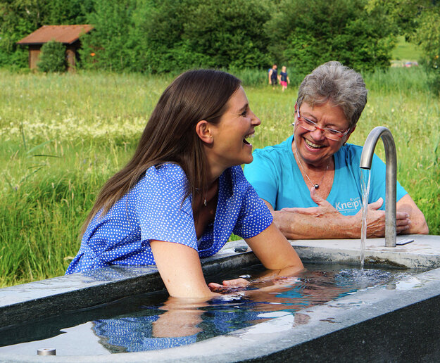 Das Bild zeigt zwei Frauen, die ein Armbad an einer Kneipp-Armgussstelle machen
