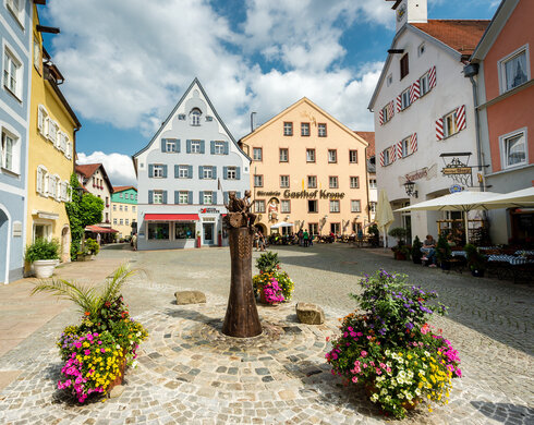 Der Schrannenplatz in Füssen mit historischen Gebäuden und Blumenkästen. Ein idyllischer Ort im Herzen der Stadt.