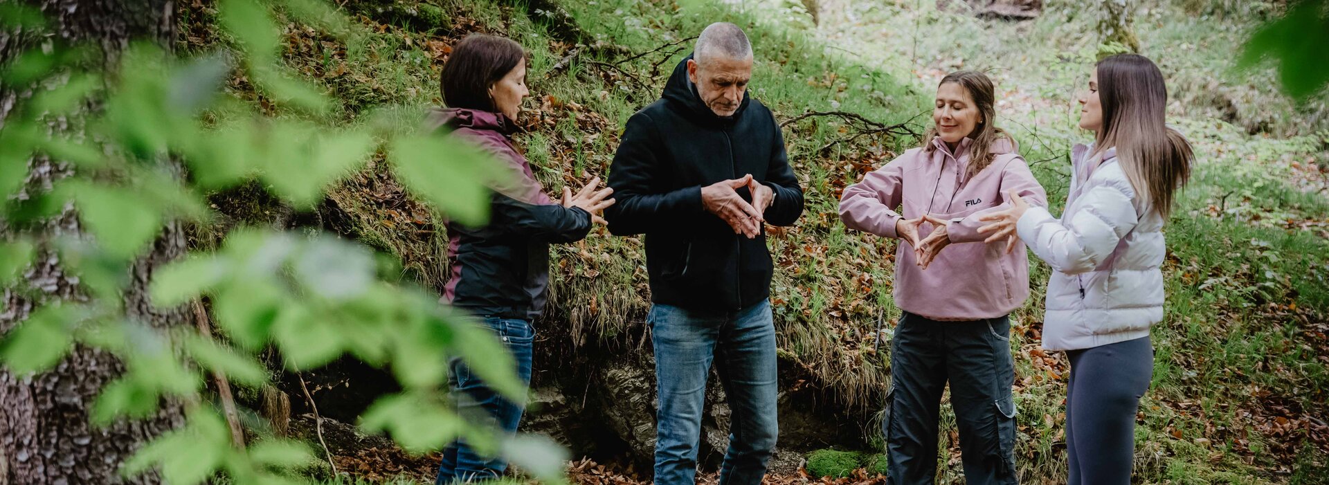 Vier Menschen im Wald machen Achtsamkeitsübungen