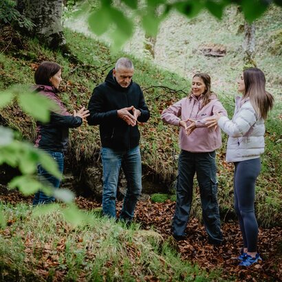 Vier Menschen im Wald machen Achtsamkeitsübungen
