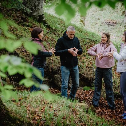 Vier Menschen im Wald machen Achtsamkeitsübungen