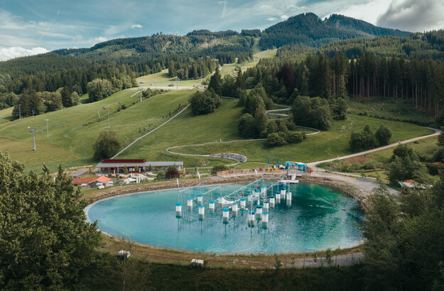 Das Bild zeigt ein Wasserbecken in einer bergigen Landschaft.