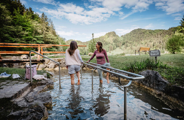 Zwei Frauen kneippen im Kneippbecken mit Bergen im Hintergrund