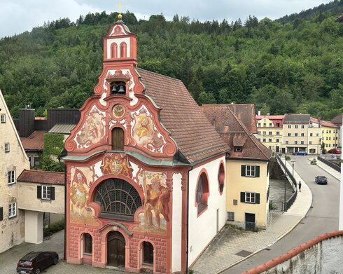 Die Heilig-Geist-Spitalkirche in Füssen beeindruckt durch ihre farbenprächtige Fassade. Das historische Gebäude befindet sich im Herzen der bayerischen Alpen.