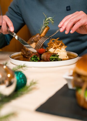 Auf dem Bild ist eine appetitliche typische Allgäuer Speise, die Schweinshaxe in Nahaufnahme zu sehen.