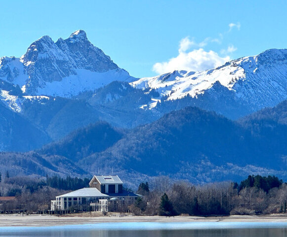 Der Forggensee im Winter mit Blick auf das Festspielhaus Neuschwanstein und die Berge