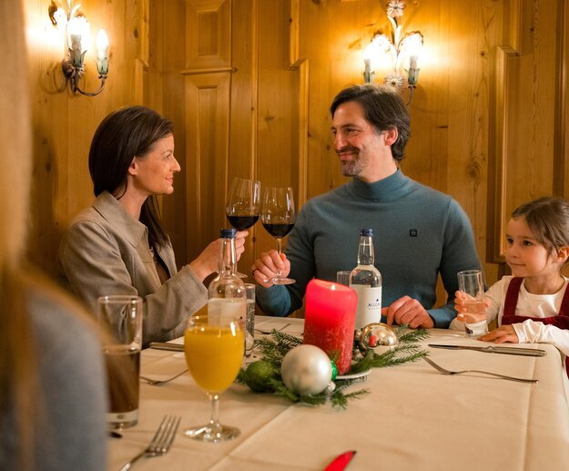 Eine Familie sitzt an einem winterlich dekorierten Tisch zum Abendessen im Restaurant.