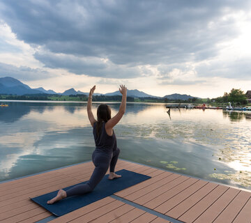 Eine Frau die auf der schwimmenden Kneippinsel am Hopfensee Yoga macht