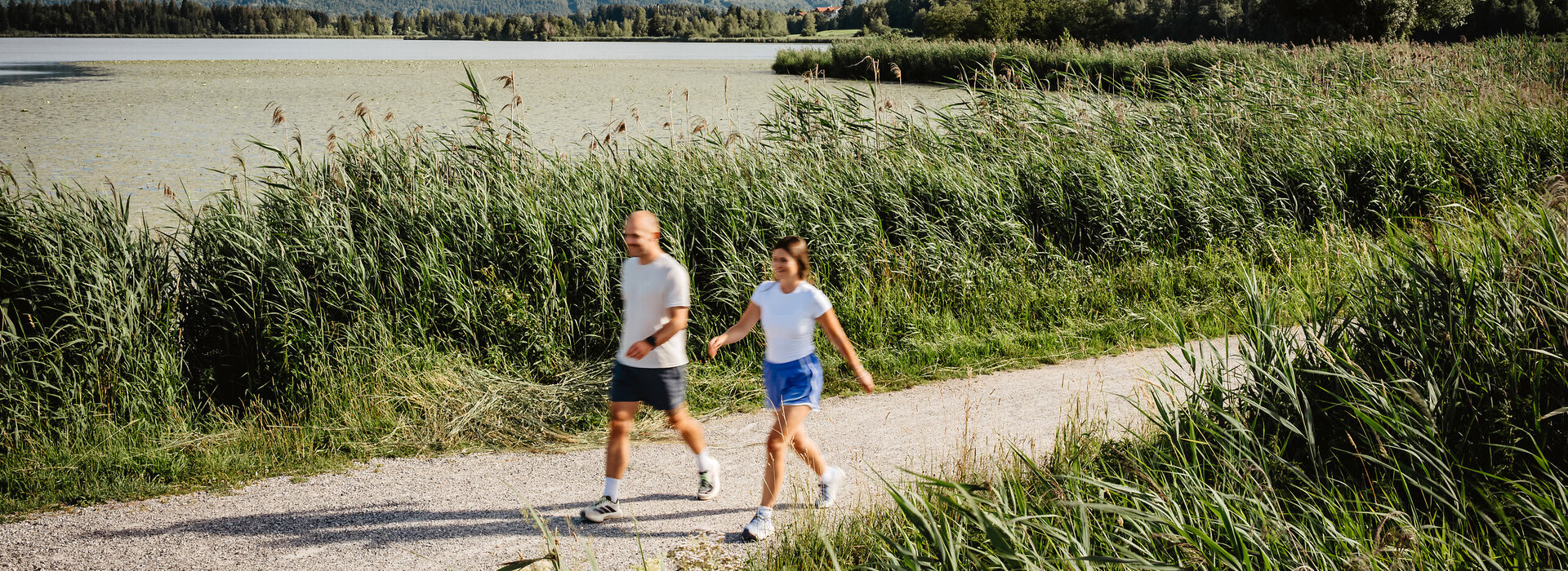Das Bild zeigt einen Mann und eine Frau, die am Hopfensee-Uferweg walken