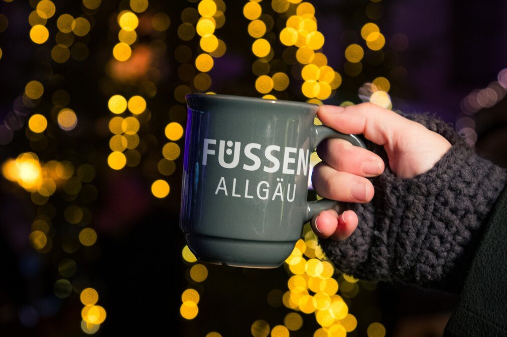 Das Foto zeigt eine Adventsmarkttasse mit Füssen-Schriftzug.