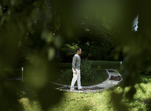 Zu den Infos Das Foto zeigt einen Mann beim achtsamen Gehen auf einem Barfußpfad..